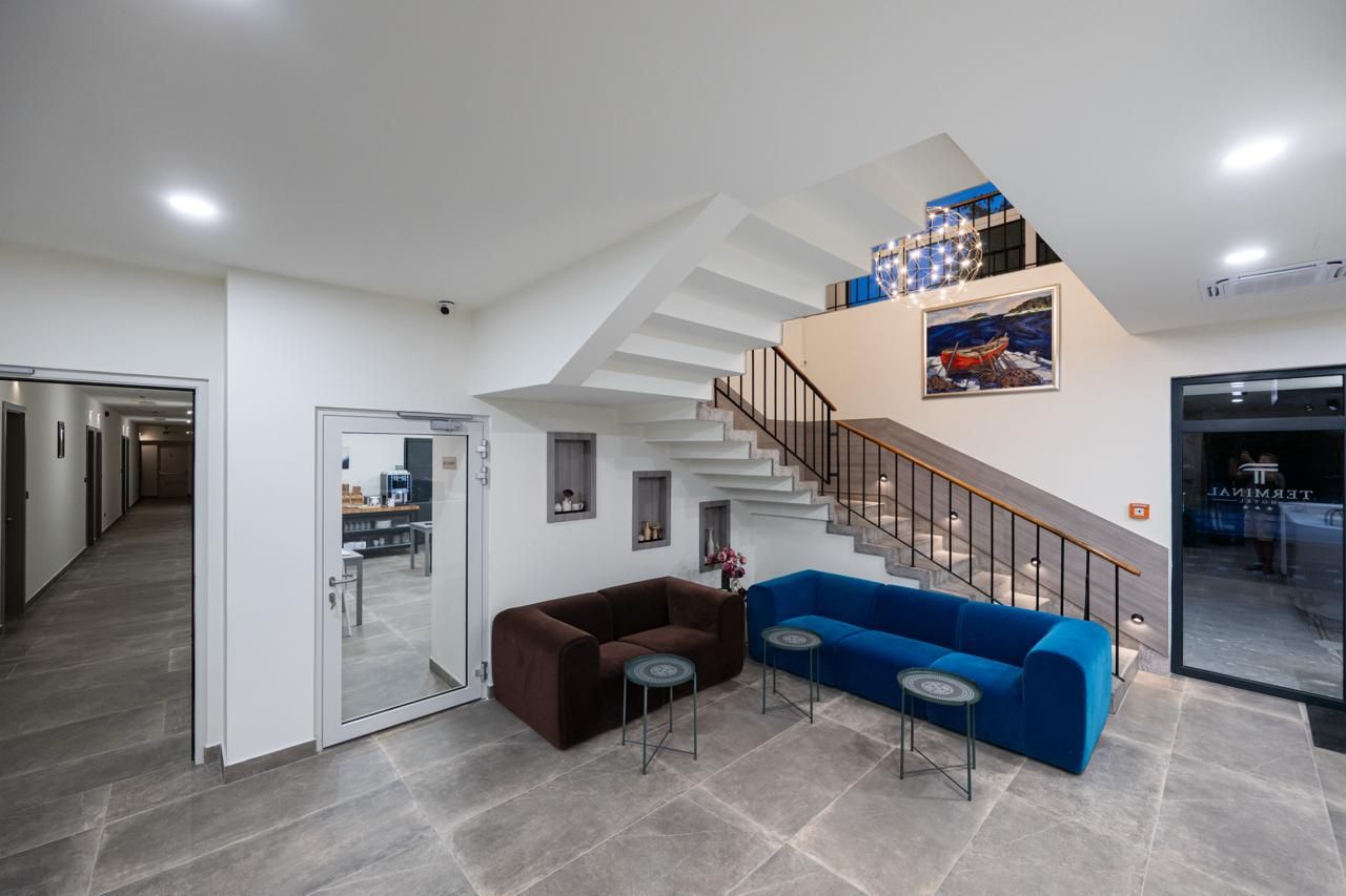 Een modern interieur met een trap, een blauwe bank en een bruine bank.