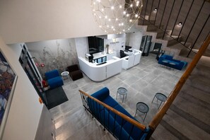 A modern reception area with a central desk, blue seating, and a staircase. - Hotel Terminal (Zadar)