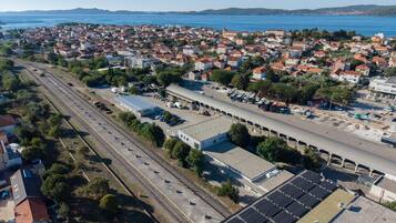 An aerial view of a coastal town with a railway station, a parking lot, and solar panels.