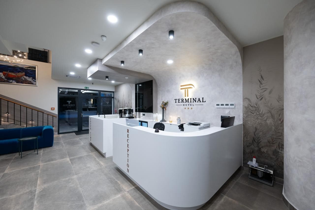 Un mostrador de recepción con diseño moderno, una escalera a la izquierda y un cuadro en la pared.