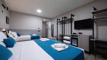 Een hotelkamer met twee bedden, een bureau, een televisie en een kledingkast.