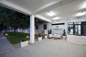 A modern hotel entrance with a reception desk, seating area, and a staircase leading inside. - Hotel Terminal (Zadar)