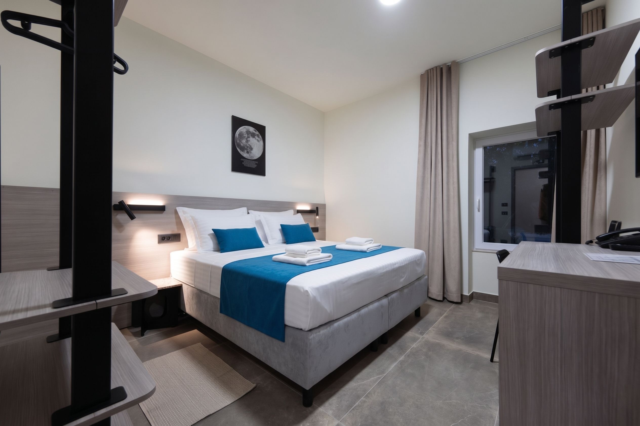 Una habitación de hotel moderna con cama, mesitas de noche, escritorio y baño.