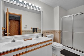 Bright full bathroom with a generous vanity and glass-enclosed shower. - Big Bass Lake • Shared Pool + Fire Pit + Game Room | Lake House Retreat (Big Bass Lake)