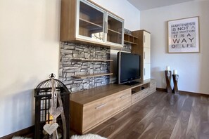 Ein modernes Wohnzimmer mit Steinwand, Flachbildfernseher, Holzausbau und einem motivierenden Zitat an der Wand.