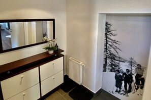 A hallway with a mirror, a radiator, a black mat, and a wall with a black and white photo. - Holiday apartment with 1 bedroom (Goldegg)