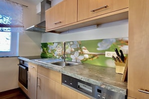 Una cocina con gabinetes de madera, un lavamanos de acero inoxidable y un lavavajillas.