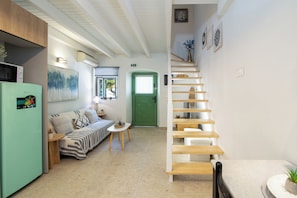 Un intérieur moderne avec un canapé, une table à manger, un escalier et une porte verte.