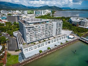 A multi-story hotel with a waterfront view, a parking lot, and a body of water in the background. - 79 Harbour Lights with Parkland & Marina Views (Cairns City)