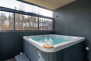 A hot tub with a view of a forest through a large window. - Levi North Apartment D4 by Aavalevi (Levi)