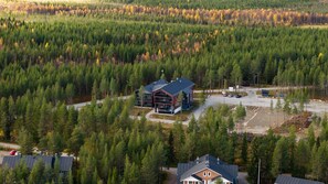 Un chalet moderne doté d’un grand bâtiment central, entouré d’une forêt dense.
