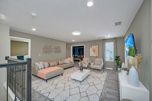 A modern living room with a sectional sofa, a coffee table, and a flat-screen TV. - 9 Bed Home Storey Lake 9 Bedroom Home (Kissimmee)