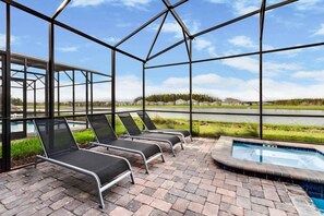 A covered outdoor area with lounge chairs and a swimming pool. - 9 Bed Home Storey Lake 9 Bedroom Home (Kissimmee)