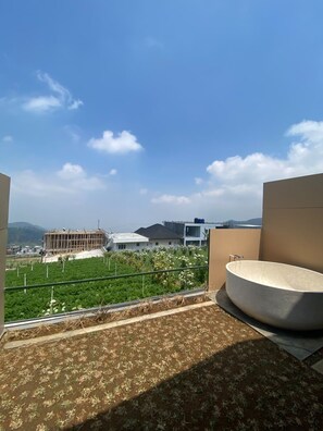Terraza en la azotea con vistas a edificios y colinas, un espacio de estar circular y una barandilla de metal.