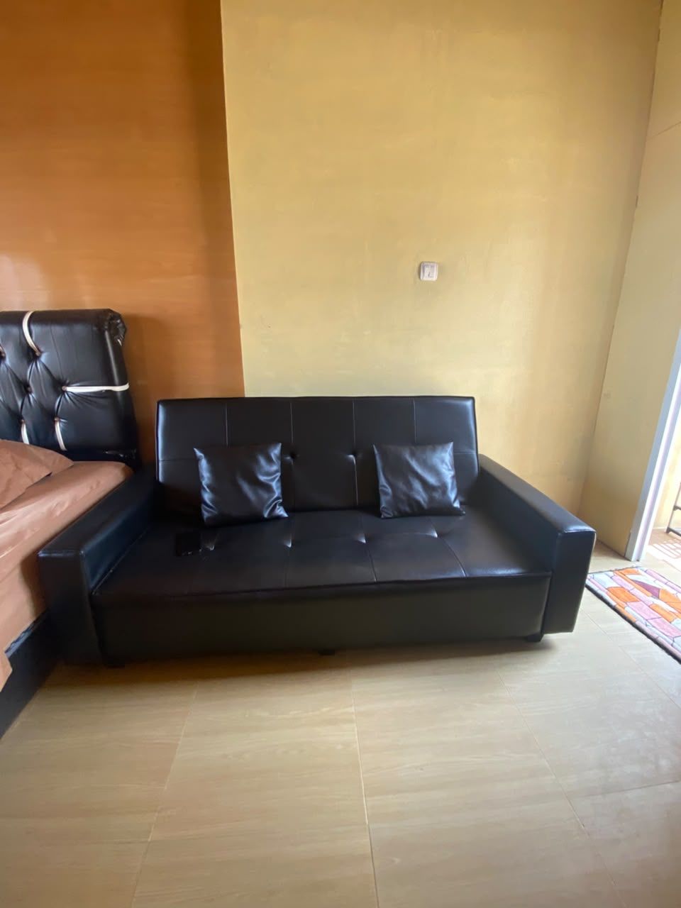 Une pièce avec un canapé en cuir noir, un fauteuil en cuir marron et un plancher en bois.