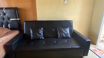 Une pièce avec un canapé en cuir noir, un fauteuil en cuir marron et un plancher en bois.