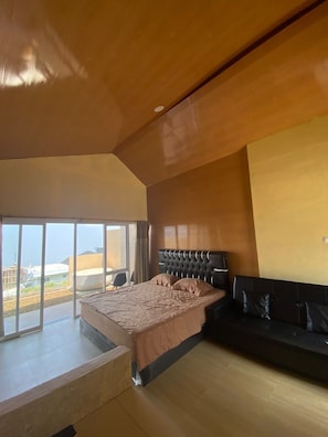 Un dormitorio moderno con una cama grande, un sofá y un balcón con vistas.