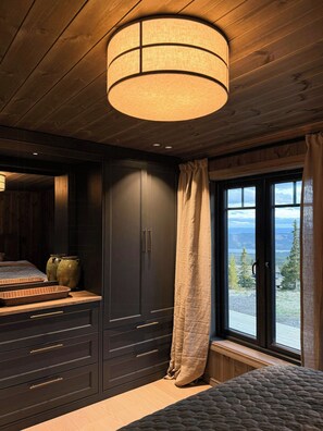 A bedroom with a large window, wooden ceiling, and a bed with a quilted cover. - Family cabin by the ski trails on Sjusjøen (Sjusjøen)