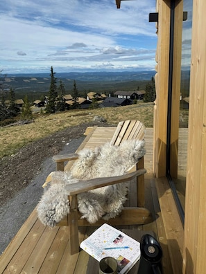 Eine Holzterrasse mit einem Hund, der auf einem Stuhl liegt, einer Karte und einer Tasse.