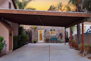 A covered patio area with a stone wall, a bench, and potted plants. - Urban San Diego Retreat • Near Balboa Park + Beaches + Downtown | Casa Marlow (San Diego)