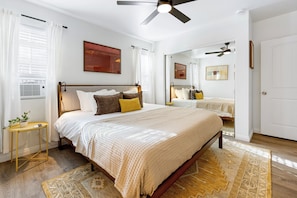 A bedroom with a bed, bedside tables, a ceiling fan, and a large mirror. - Urban San Diego Retreat • Near Balboa Park + Beaches + Downtown | Casa Marlow (San Diego)