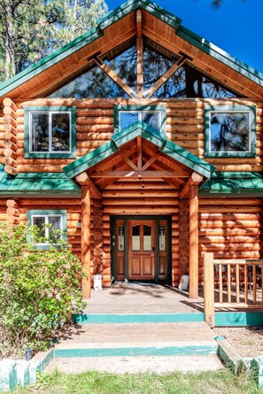 A log cabin with a front porch, large windows, and a green roof. - New! Bearadise ~ Timberlodge Mountain Retreat (Big Bear Lake)