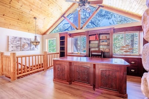 A spacious room with a wooden ceiling, a large wooden desk, and a view of trees through the windows. - New! Bearadise ~ Timberlodge Mountain Retreat (Big Bear Lake)