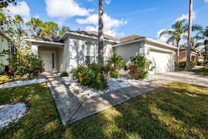 A residential house with a front yard, a driveway, and a garage. - Southern Dunes Comforts Of Home! Golf Views! 4 Bedroom Home (Haines City)