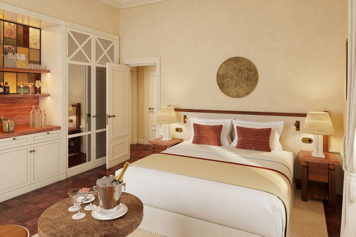 A hotel room with a bed, bedside tables, a nightstand, a round wall decoration, and a minibar.