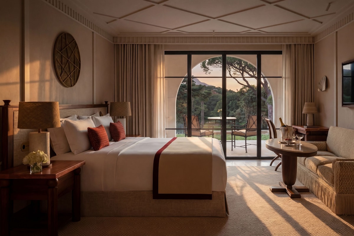 A hotel room with a large bed, a sitting area with a table, and a view of the outdoors.