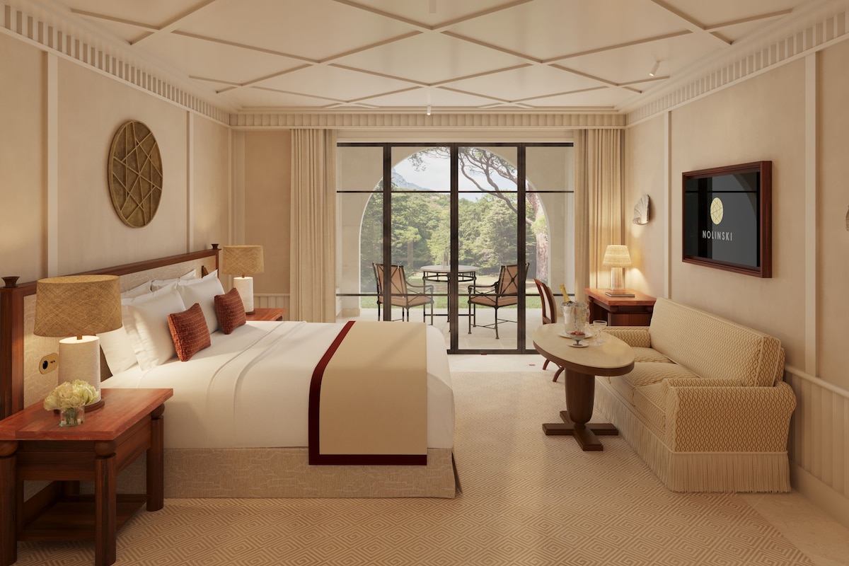 A hotel room with a large bed, a sofa, a dining table, and a view of the outdoors.
