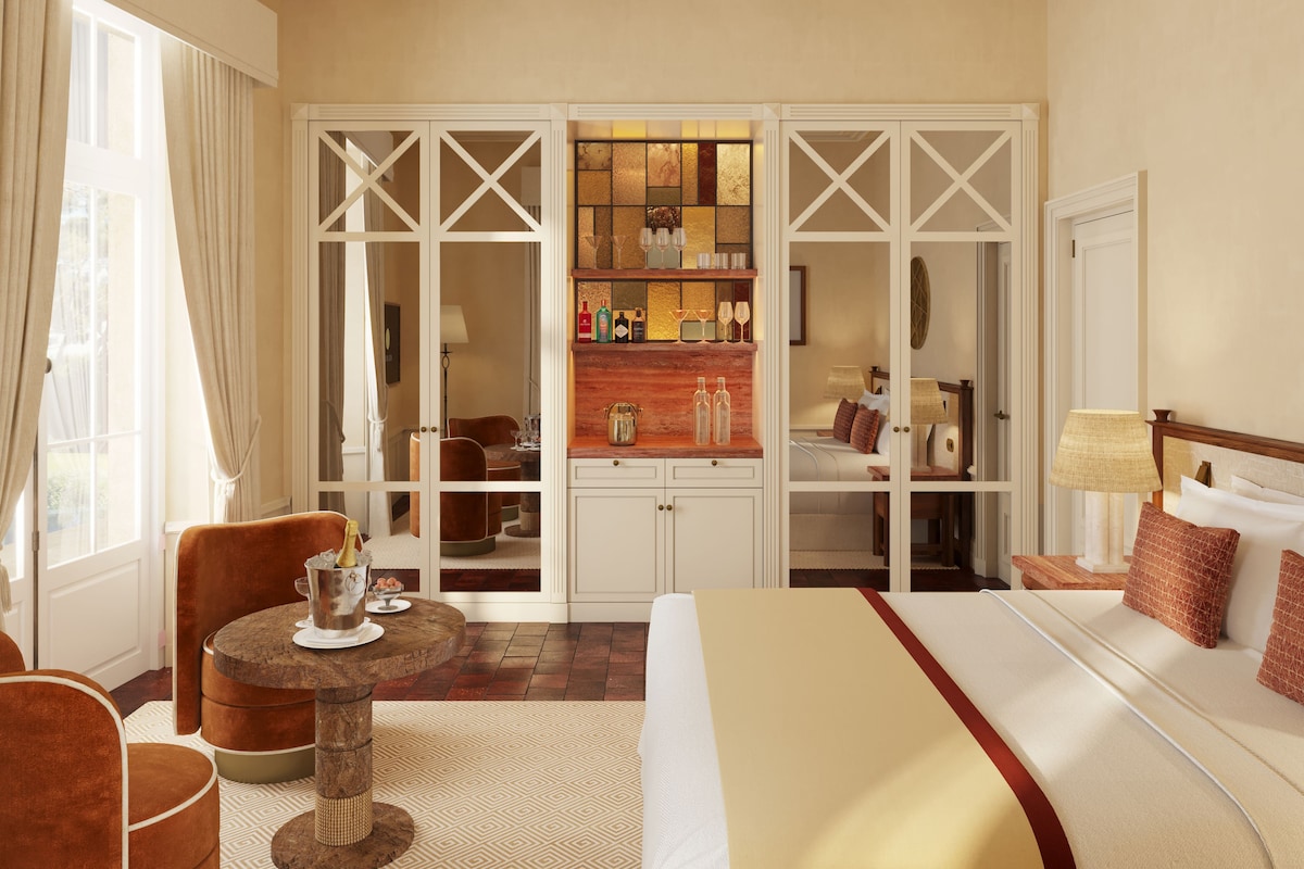 A hotel room with a bed, a seating area with a table, a wardrobe, and a view through a glass door.