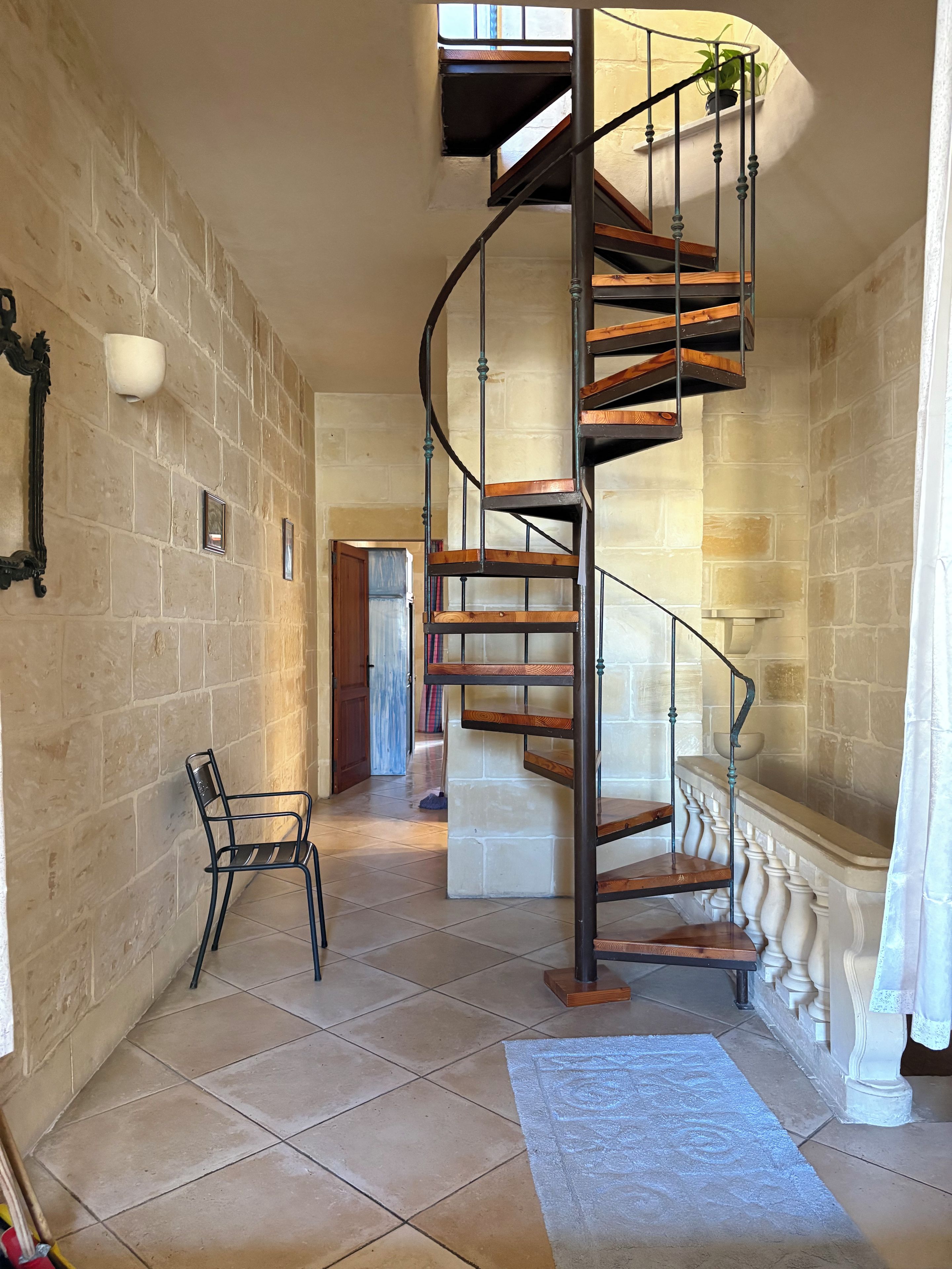 A spiral staircase with wooden steps and metal railings, leading to an upper floor.
