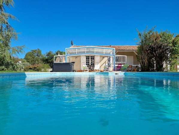 Una piscina amb plataforma de salts, gandules i un edifici amb teulada emblenquinada.