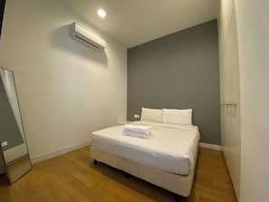 Een slaapkamer met een bed, een airconditioning en een houten vloer.