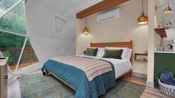 A tent-style room with a bed, a small table, and a hanging light fixture.