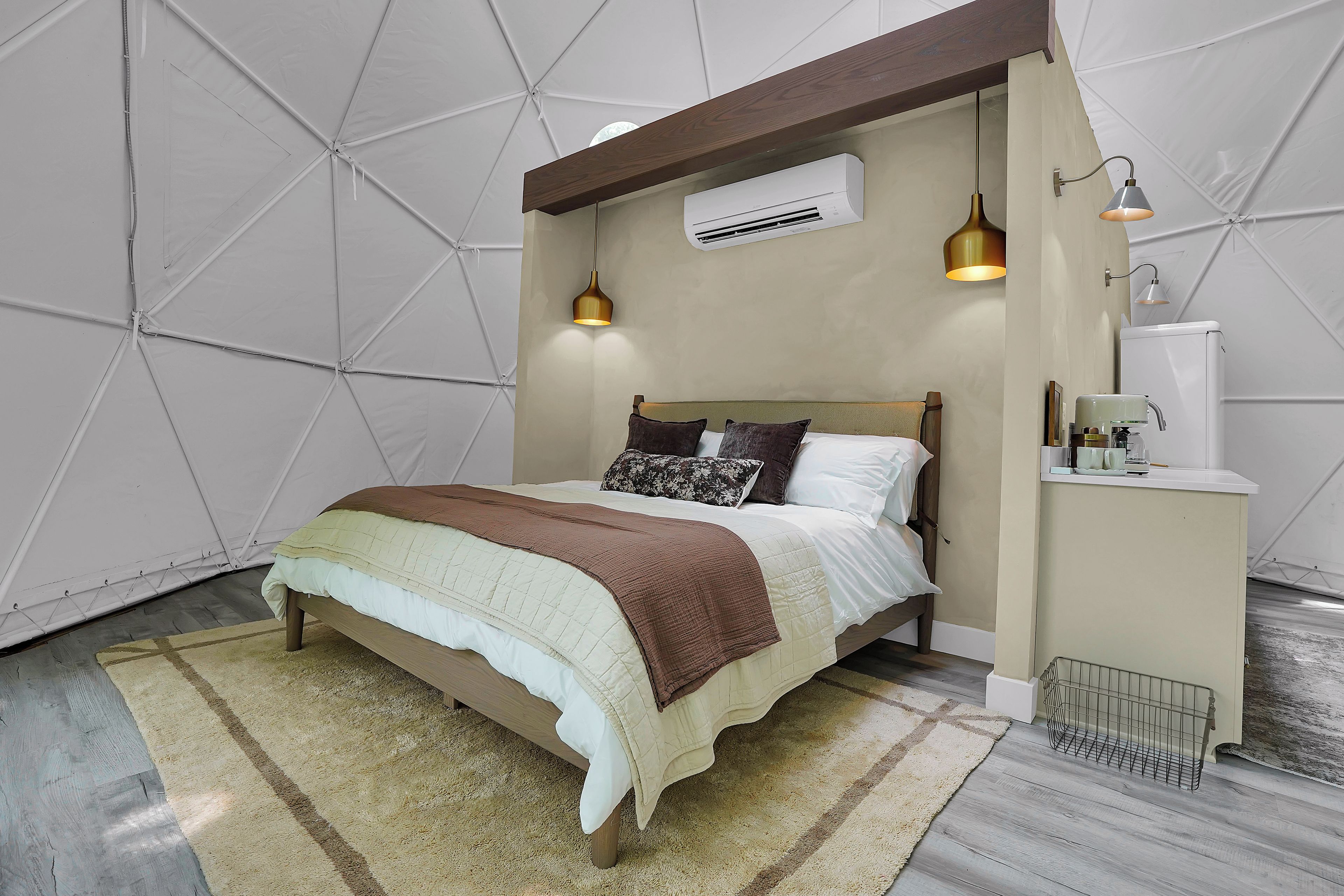 Un dormitorio con cama, mesita de noche, lámpara y aire acondicionado.