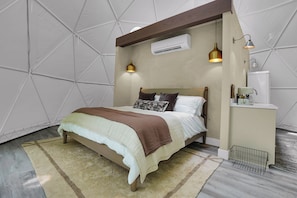 Un dormitorio con cama, mesita de noche, lámpara y aire acondicionado.
