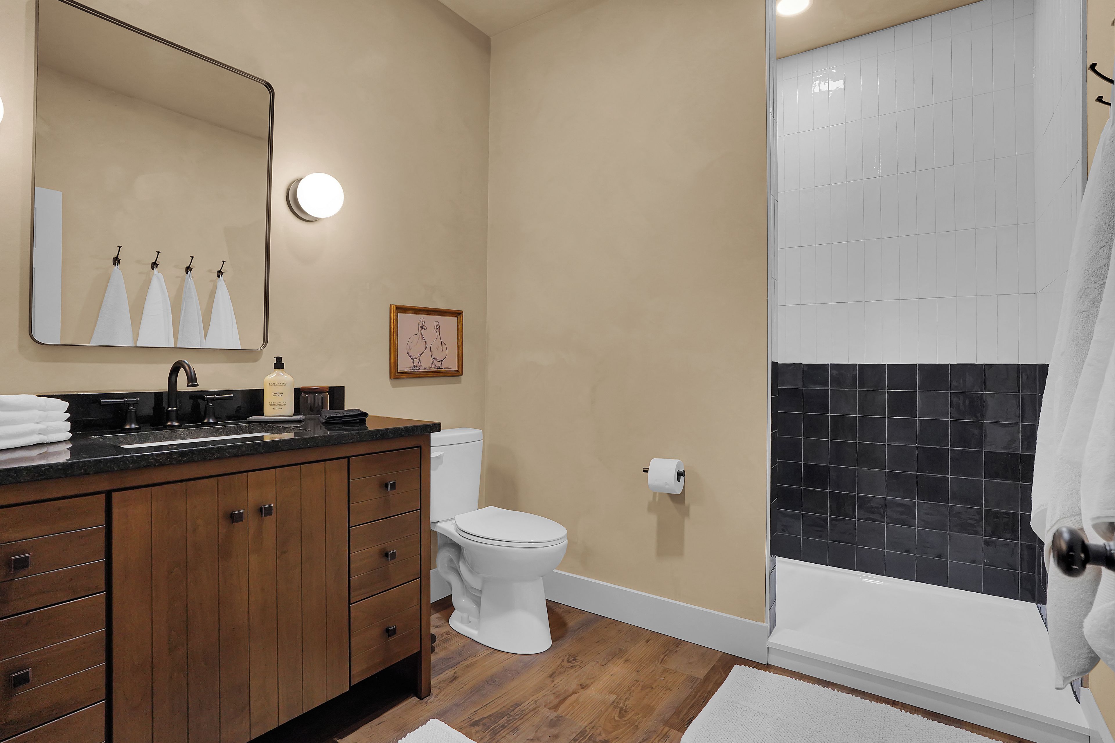 A bathroom with a wooden vanity, a toilet, a sink, and a shower area.