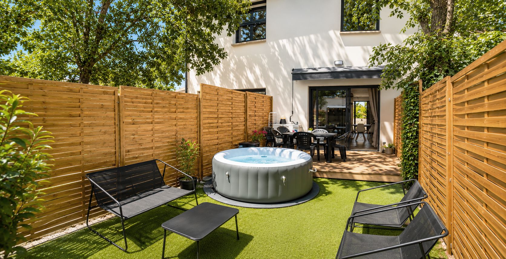 Un jardin avec un jacuzzi, un espace salon extérieur et une terrasse.