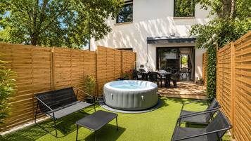 Un jardin avec un jacuzzi, un espace salon extérieur et une terrasse.