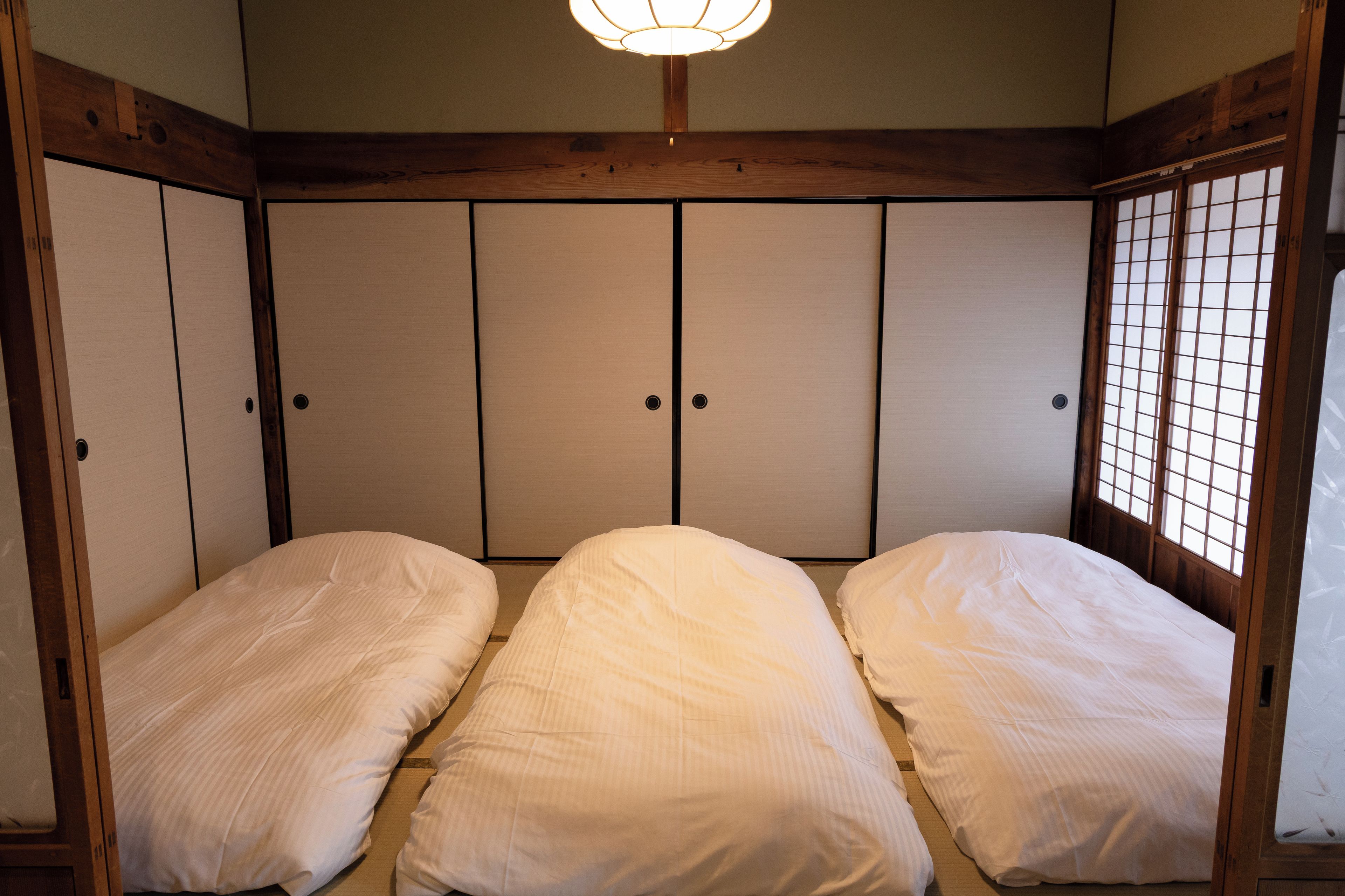A traditional Japanese room with tatami flooring, a shoji screen, and a ceiling light fixture.