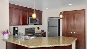 Cocina con encimeras de granito, electrodomésticos de acero inoxidable y alacenas de madera.