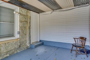 A room with a stone wall, a white door, and a blue floor. There is a wooden chair and a window with blinds. - Work, Play & Explore! Saugus Extended Stay (Saugus)