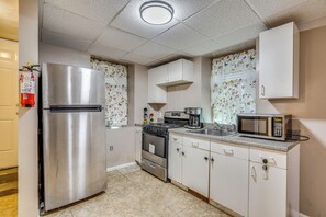 A compact kitchen with a stainless steel refrigerator, a microwave, and a stove. - Work, Play & Explore! Saugus Extended Stay (Saugus)