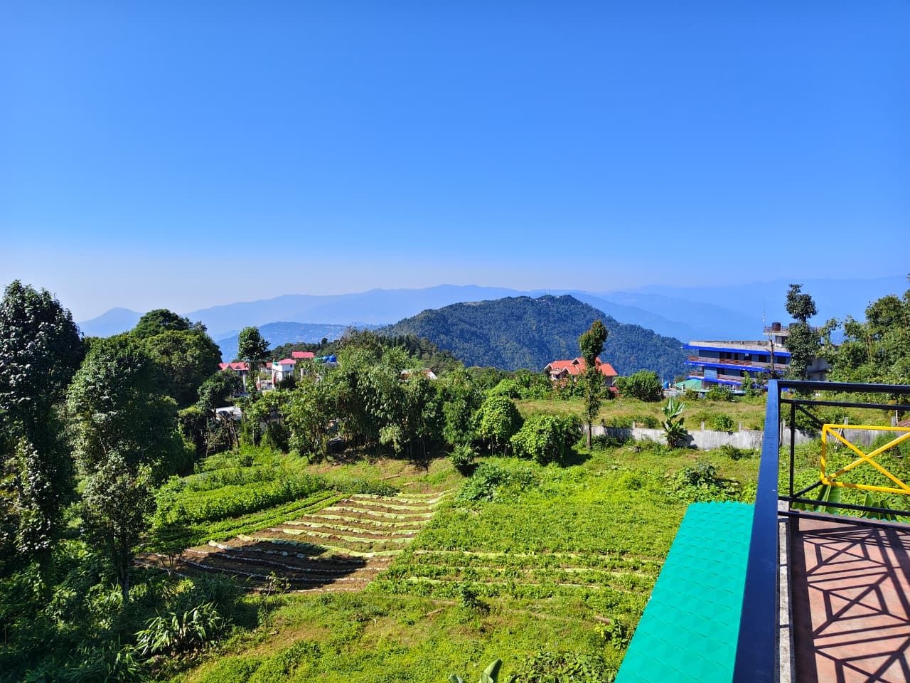 A rural landscape with terraced fields, a clear blue sky, and scattered buildings.