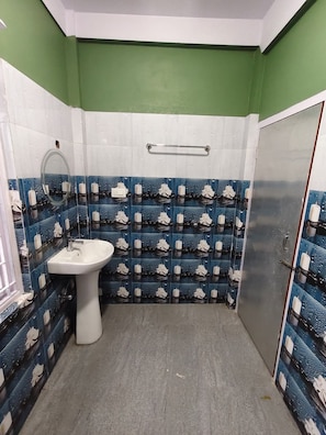 Un baño con un lavamanos pedestal blanco, un espejo y un perchero de toallas en la pared.