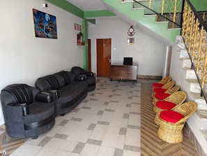 Un área de recepción con un sofá, sillas, un escritorio y una escalera.
