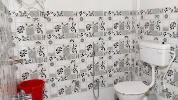A bathroom with a toilet, shower, and a red bucket.