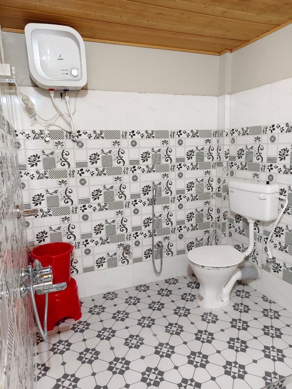 A bathroom with a toilet, shower, and a red bucket.